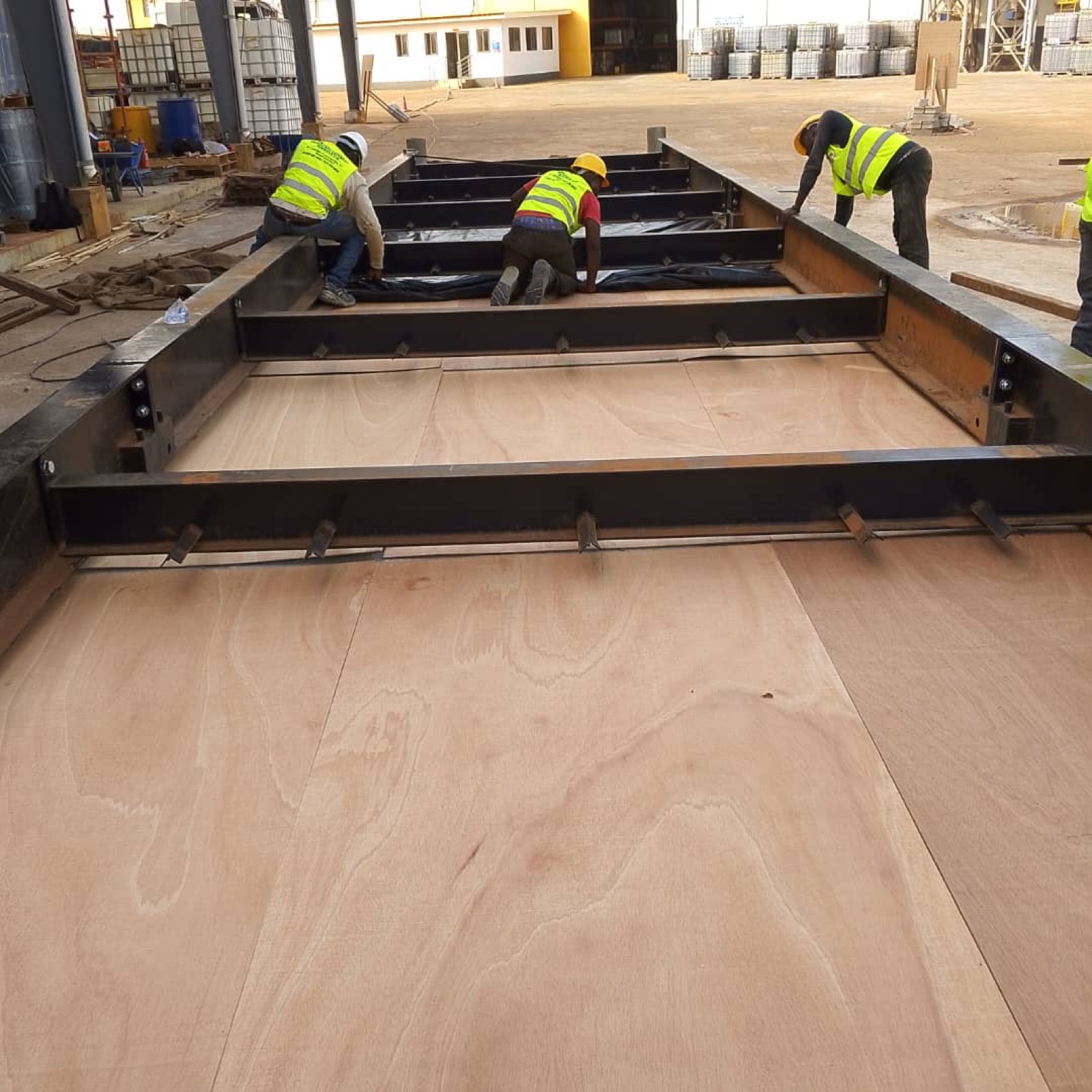 Three workers assembling a weighbridge frame