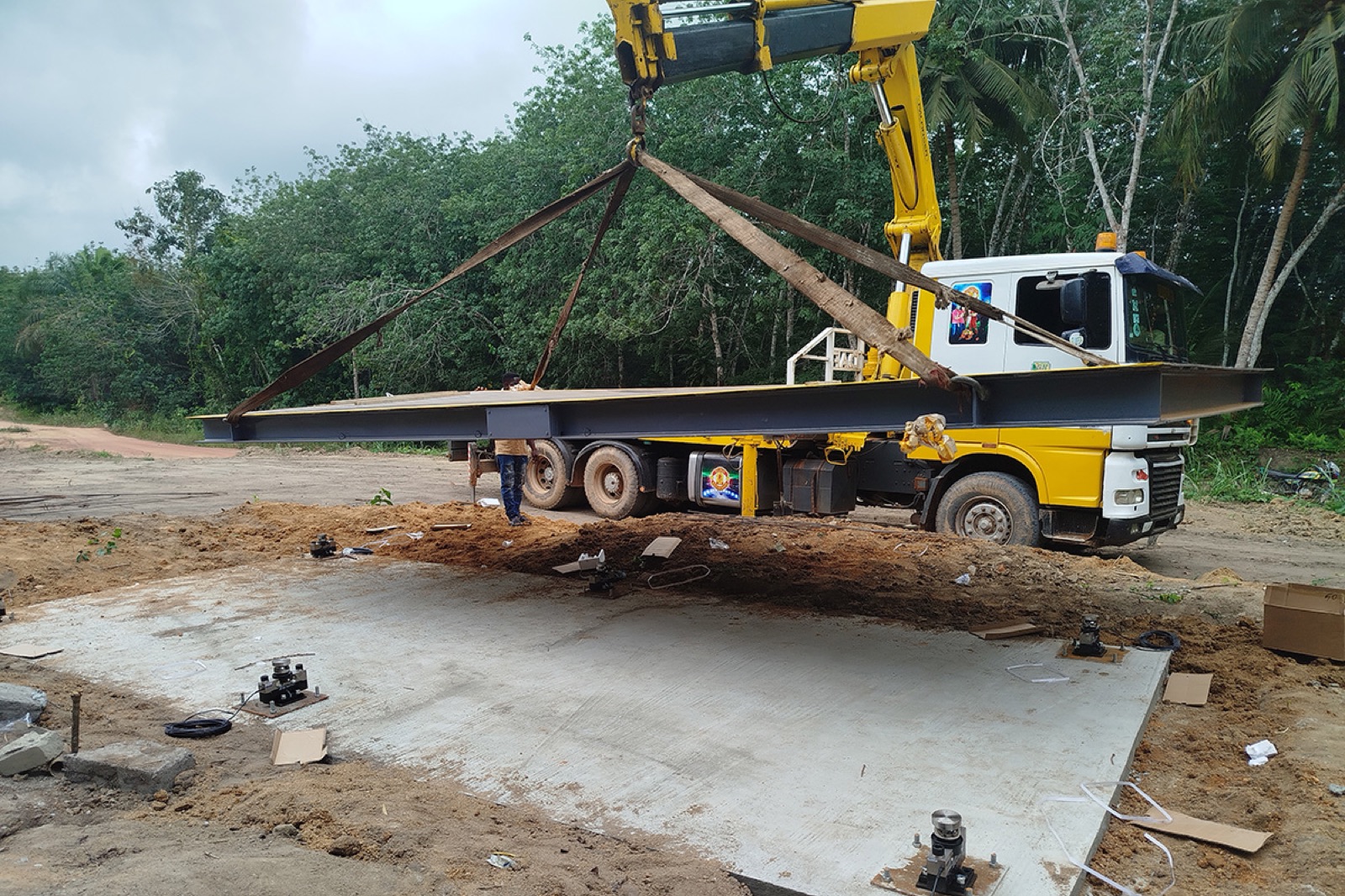 Crane lowering a weighbridge deck at a rural site